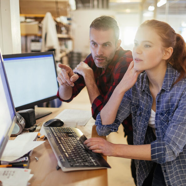 Young man and woman using a computer while working in a printing press office